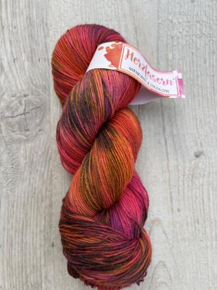 Dieses Garn wurde moeglichst farbecht fotografiert. Je nach Bildschirm koennen die Farben abweichen. Farbtoene in Worten beschrieben: kraeftiges Pink, intensives Rot, Orange, Bordeaux und dunkle Brauntoene.  ALT-Texte fuer Screenreader: 	1.	Ein Strang Wol